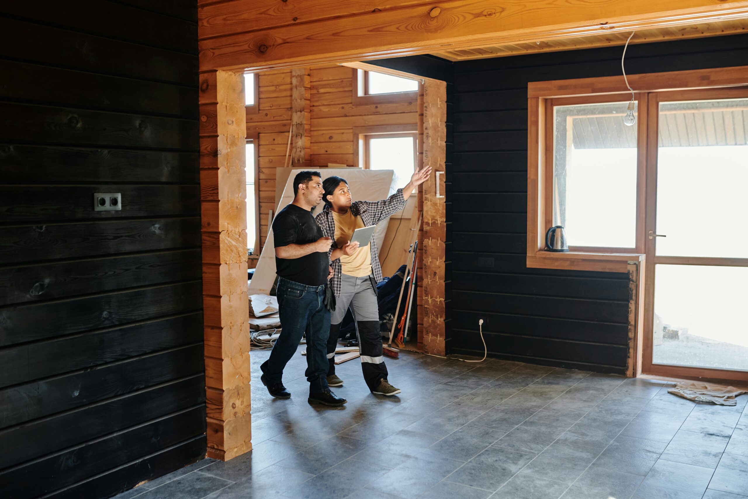 Two construction professionals discussing renovation plans inside a partially finished timber home in the UK.